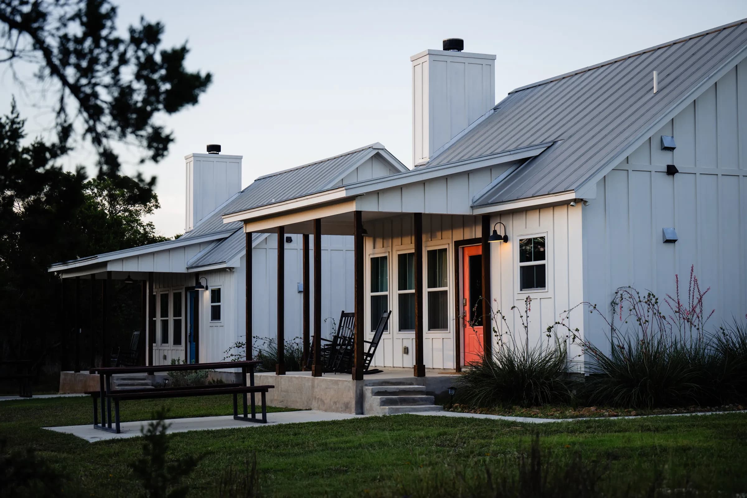 Farmhouse cottages at dusk with porch lights on at Wayside Wimberley
