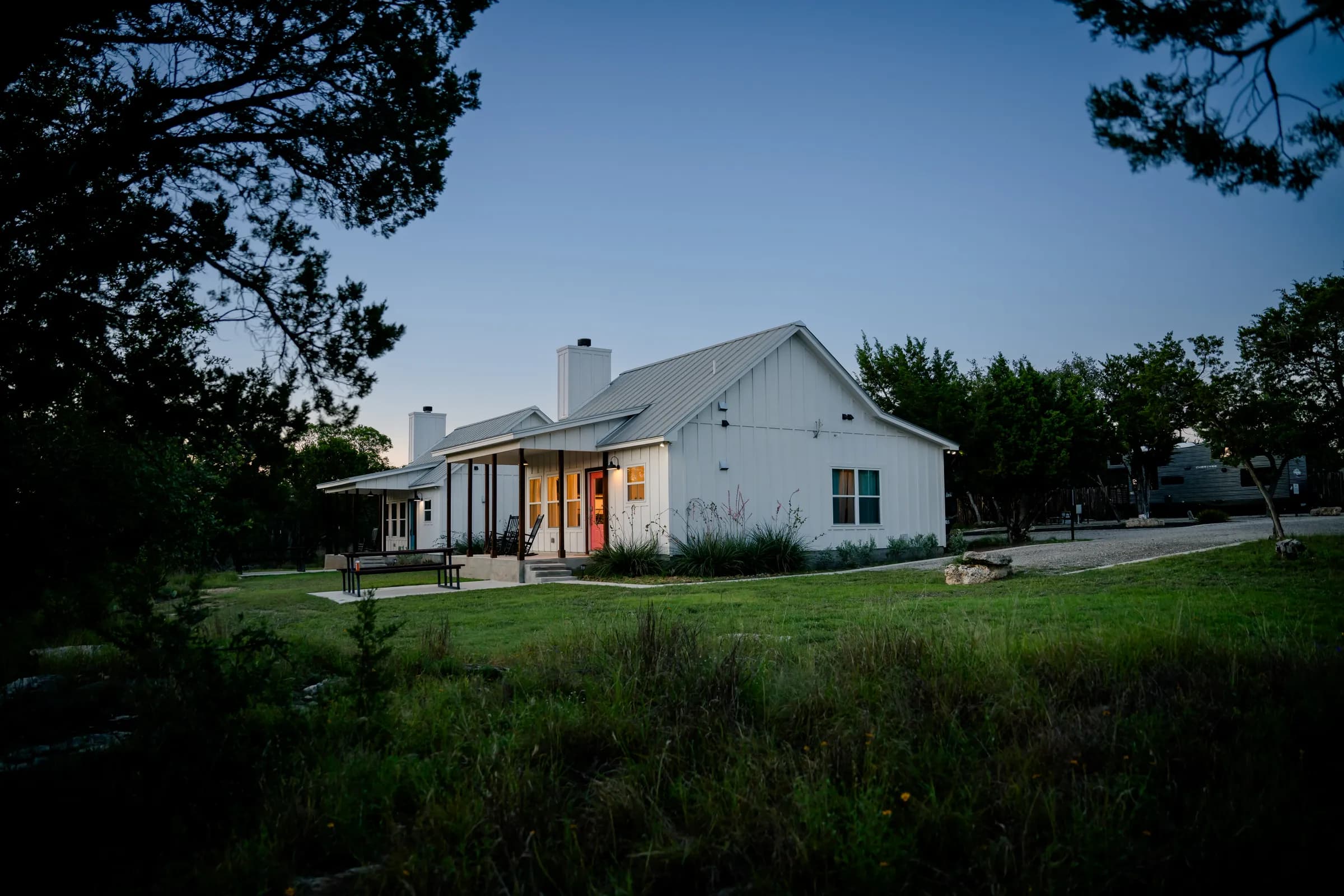Farmhouse cottage at twilight with porch lights glowing at Wayside Wimberley